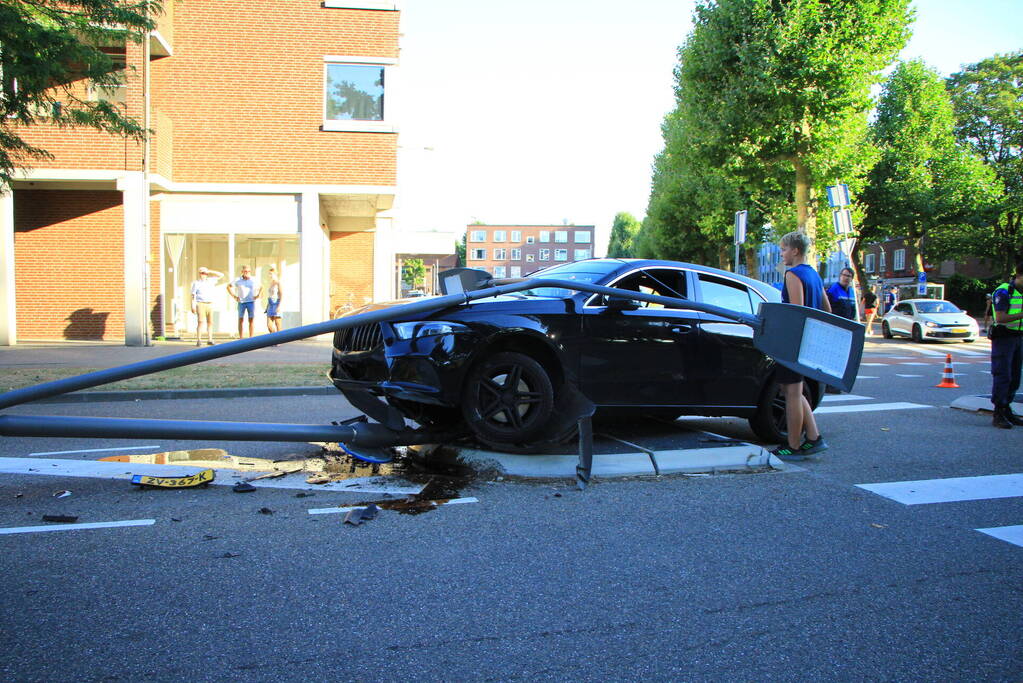 Personenauto uit de bocht, lantaarnpaal geraakt