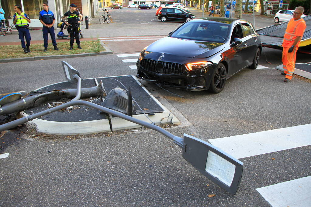 Personenauto uit de bocht, lantaarnpaal geraakt