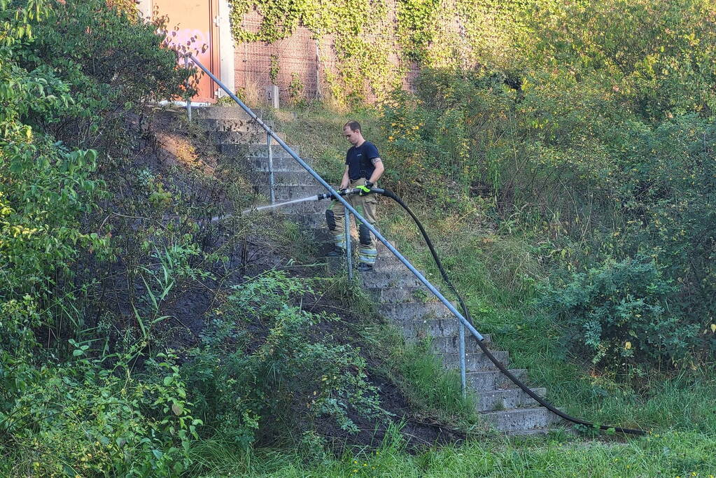 Brandweer blust bermbrand naast treinspoor