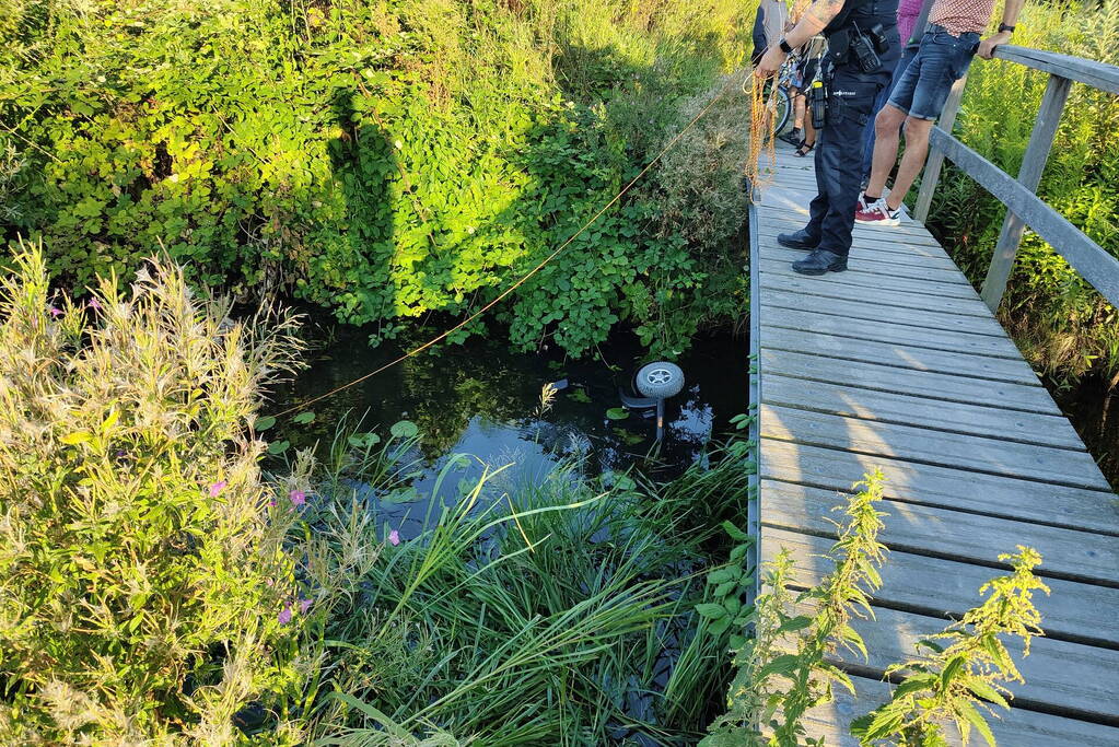 Man op scootmobiel rijdt vanaf brug het water in