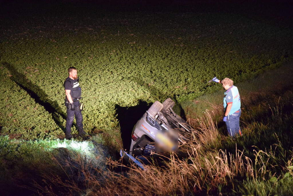 Auto op zijn kop in sloot naast talud