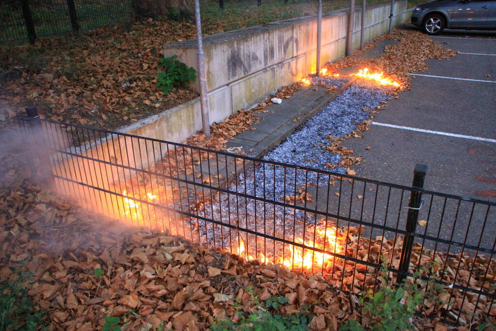 Bladeren vliegen in brand op parkeerterrein