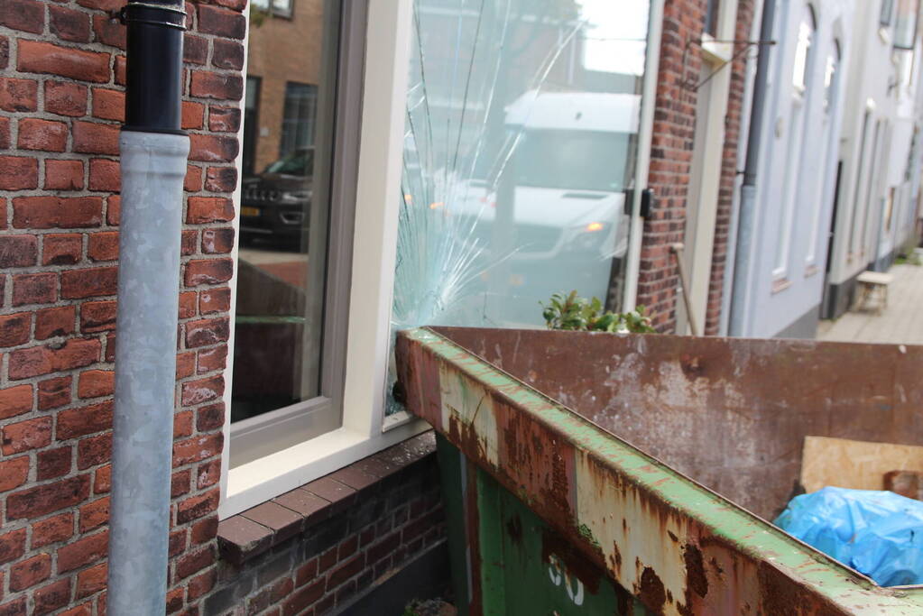 Pakketbezorger botst tegen bouwcontainer en knalt tegen woning