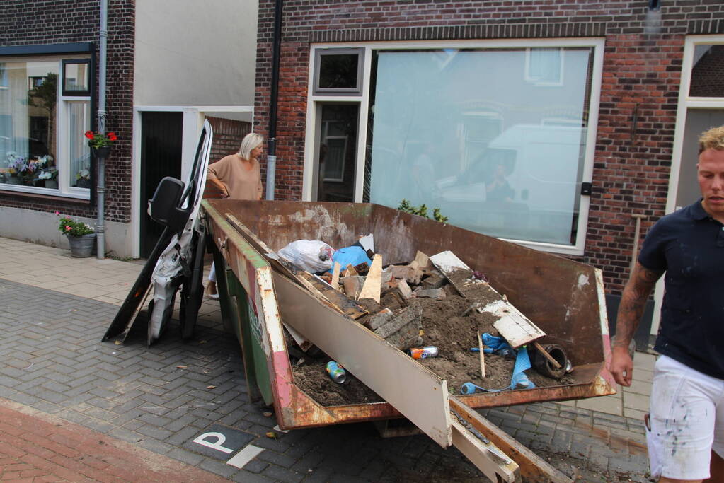 Pakketbezorger botst tegen bouwcontainer en knalt tegen woning