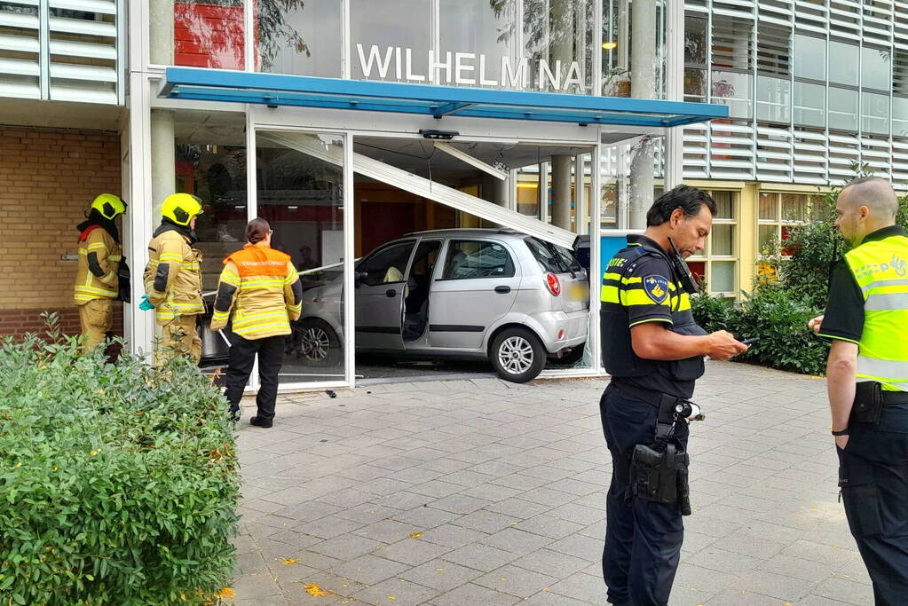 Bestuurster ramt met auto entree flatgebouw