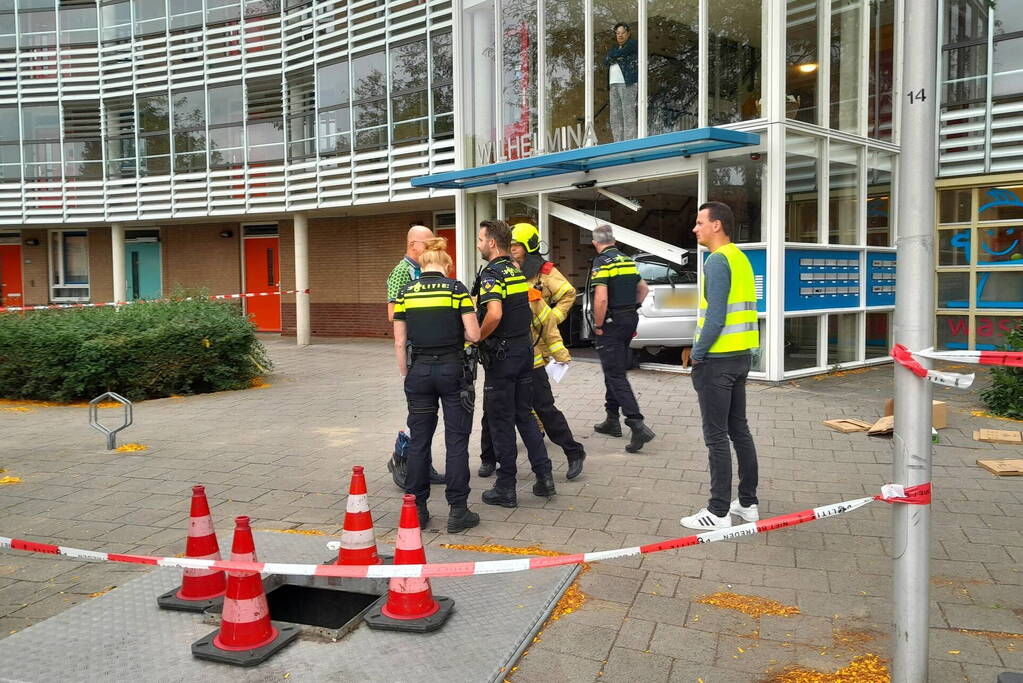 Bestuurster ramt met auto entree flatgebouw