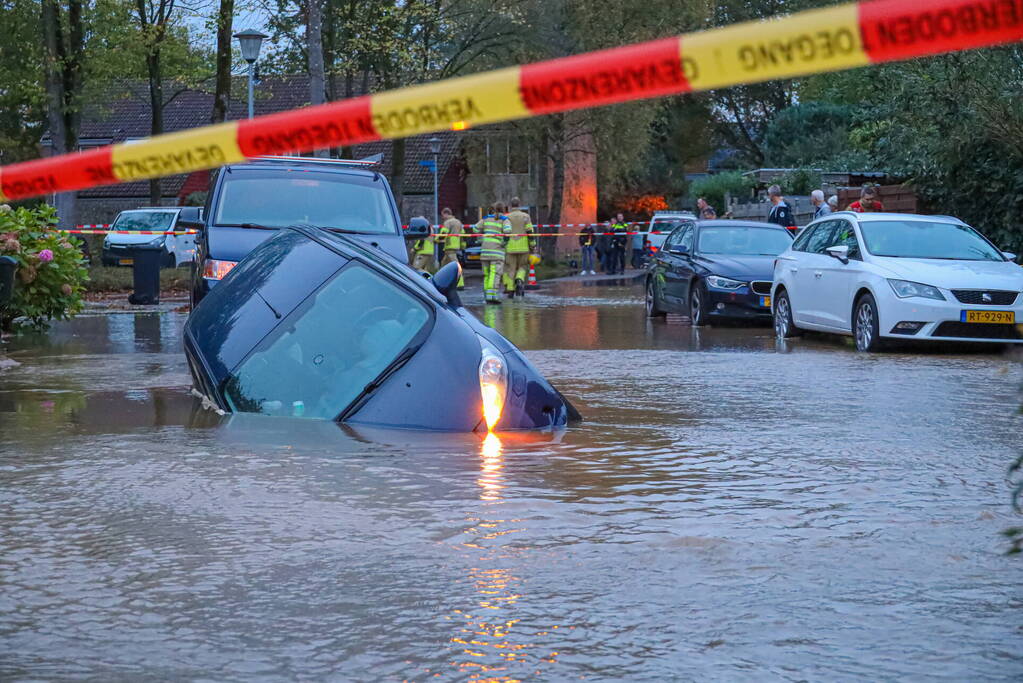Auto zakt in sinkhole door gesprongen hoofdwaterleiding