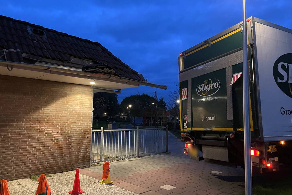 Vrachtwagen rijdt tegen dak van gebouw