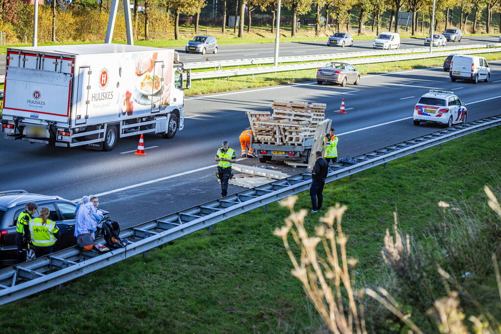 Automobilist verliest overbeladen aanhangwagen met pallets en crasht