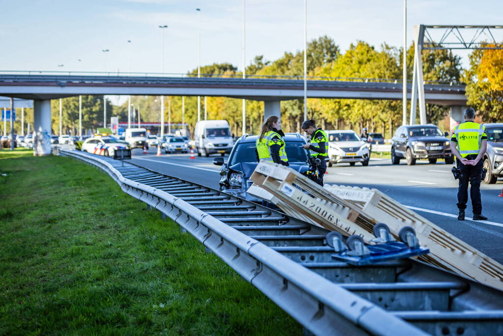 Automobilist verliest overbeladen aanhangwagen met pallets en crasht