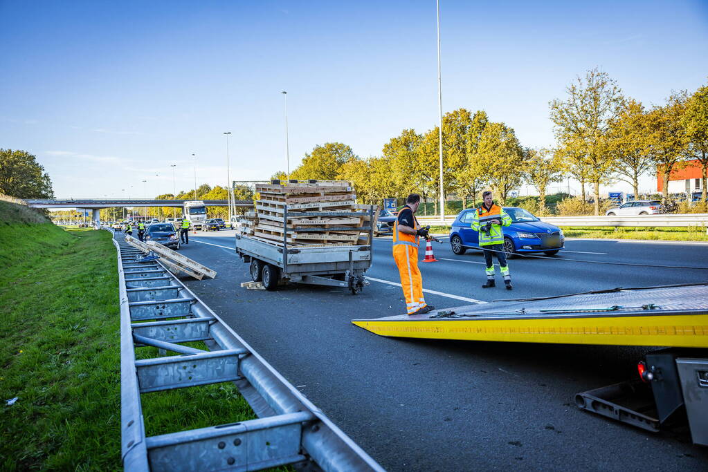 Automobilist verliest overbeladen aanhangwagen met pallets en crasht