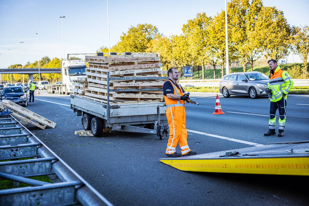 Automobilist verliest overbeladen aanhangwagen met pallets en crasht