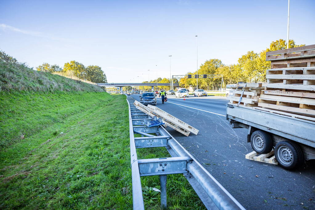 Automobilist verliest overbeladen aanhangwagen met pallets en crasht