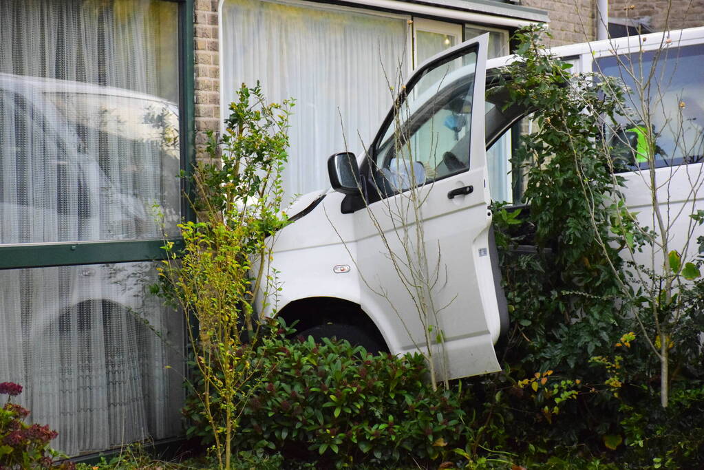 Taxibus met kinderen rijdt tegen woning