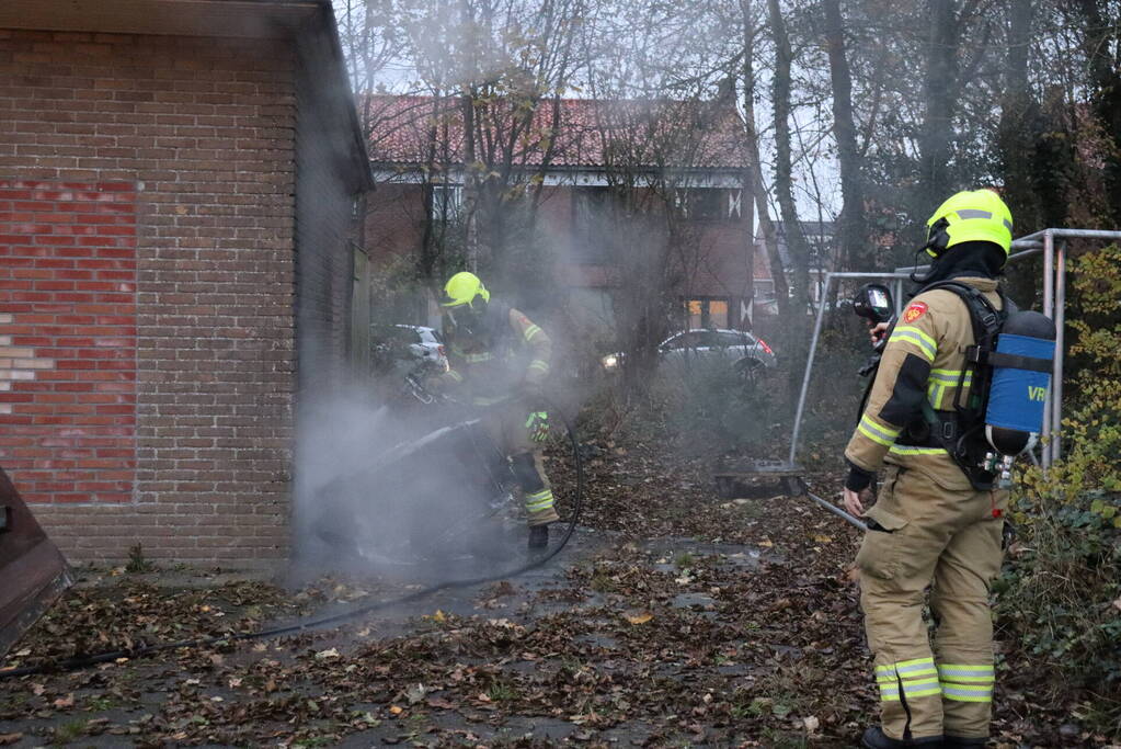 Wasmachine in brand tegen gebouw