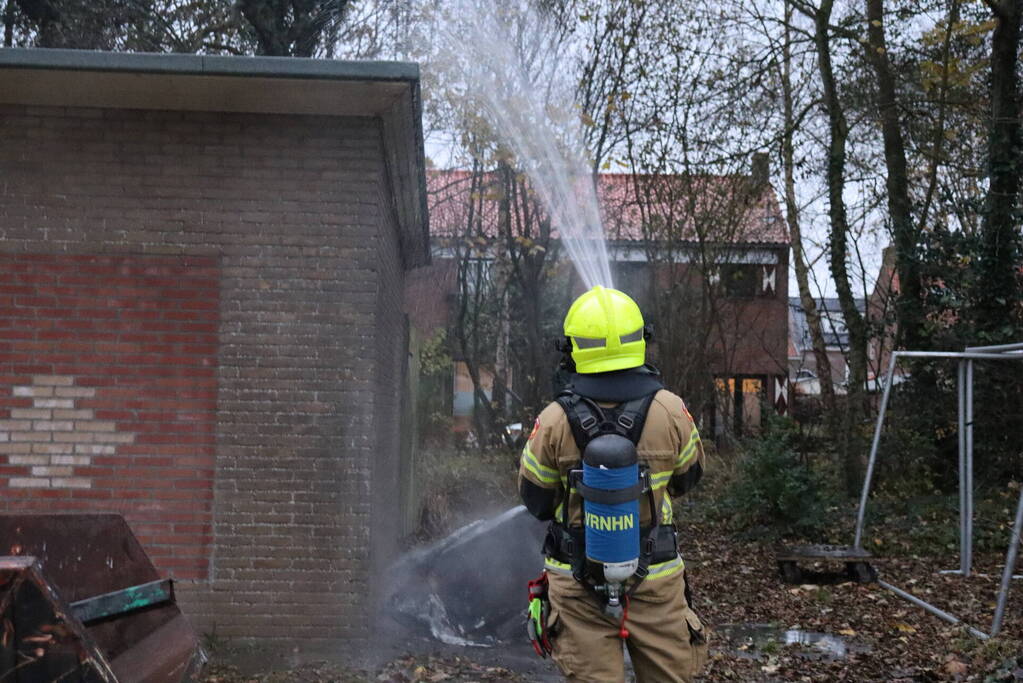 Wasmachine in brand tegen gebouw