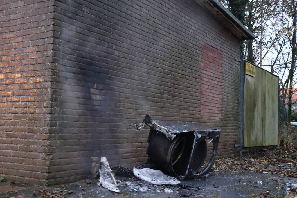 Wasmachine in brand tegen gebouw