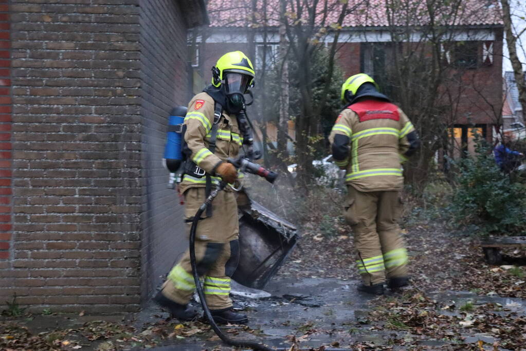 Wasmachine in brand tegen gebouw