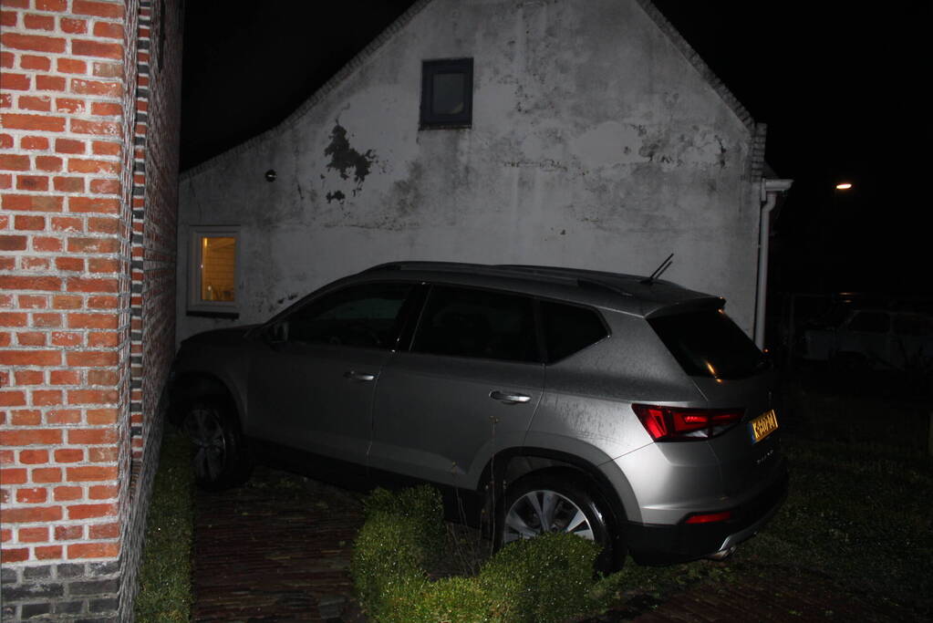 Auto glijdt door tegen woning