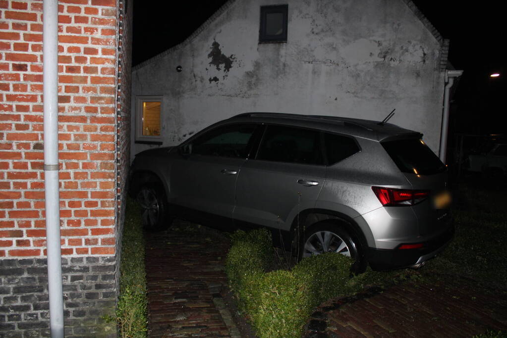 Auto glijdt door tegen woning