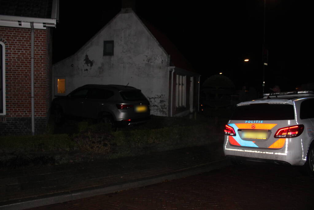 Auto glijdt door tegen woning