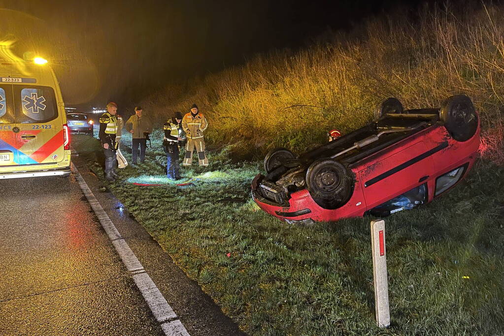 Auto belandt op de kop naast weg