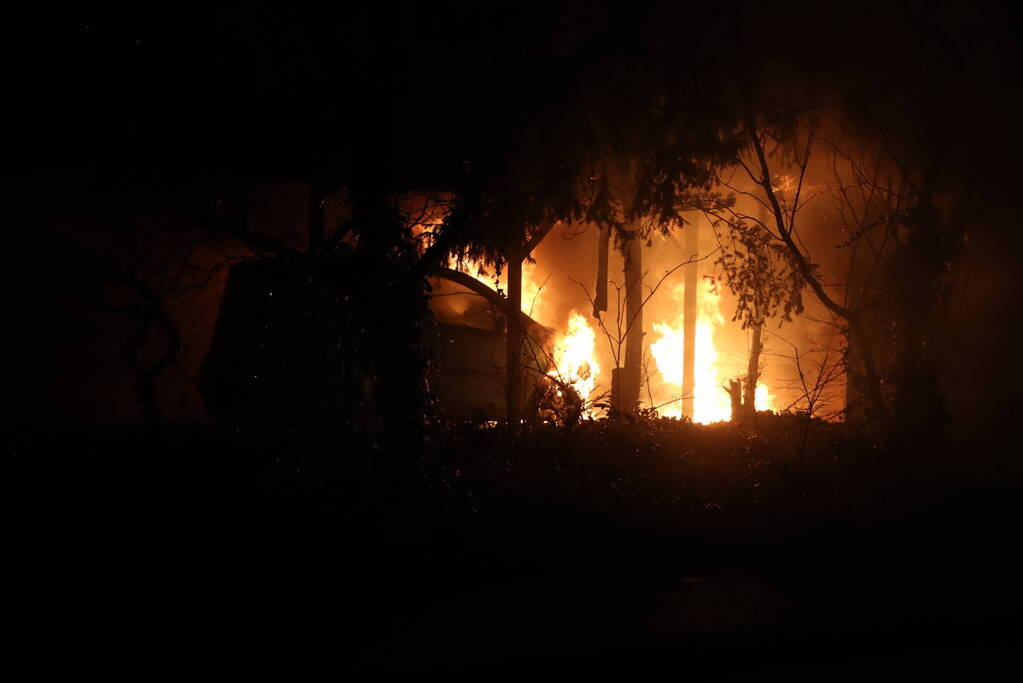Personenauto vat vlam onder carport