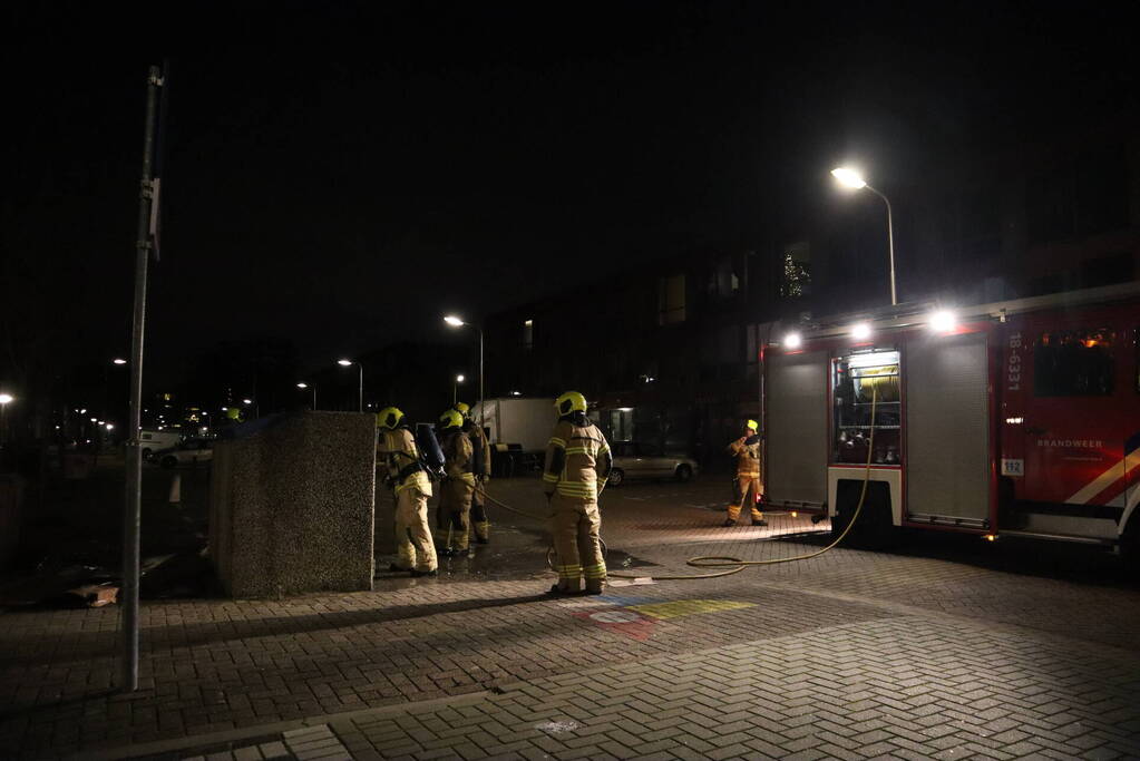 Brandweer blust brandende papiercontainer