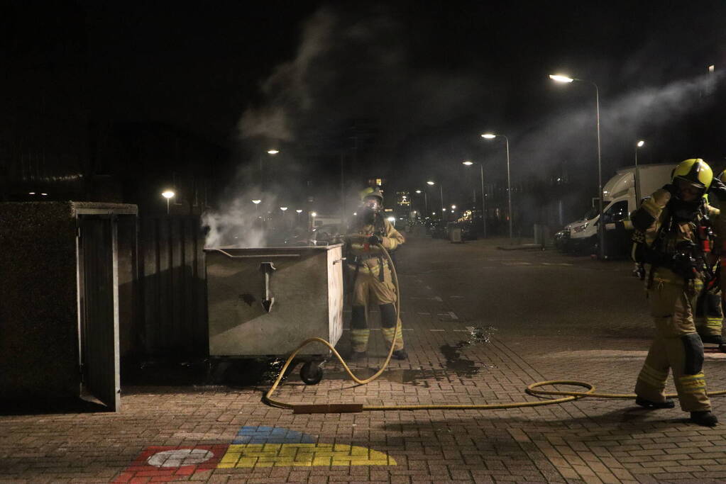 Brandweer blust brandende papiercontainer