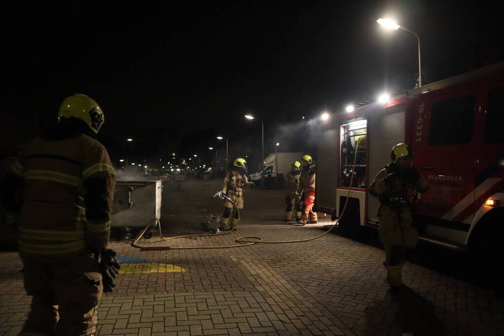 Brandweer blust brandende papiercontainer
