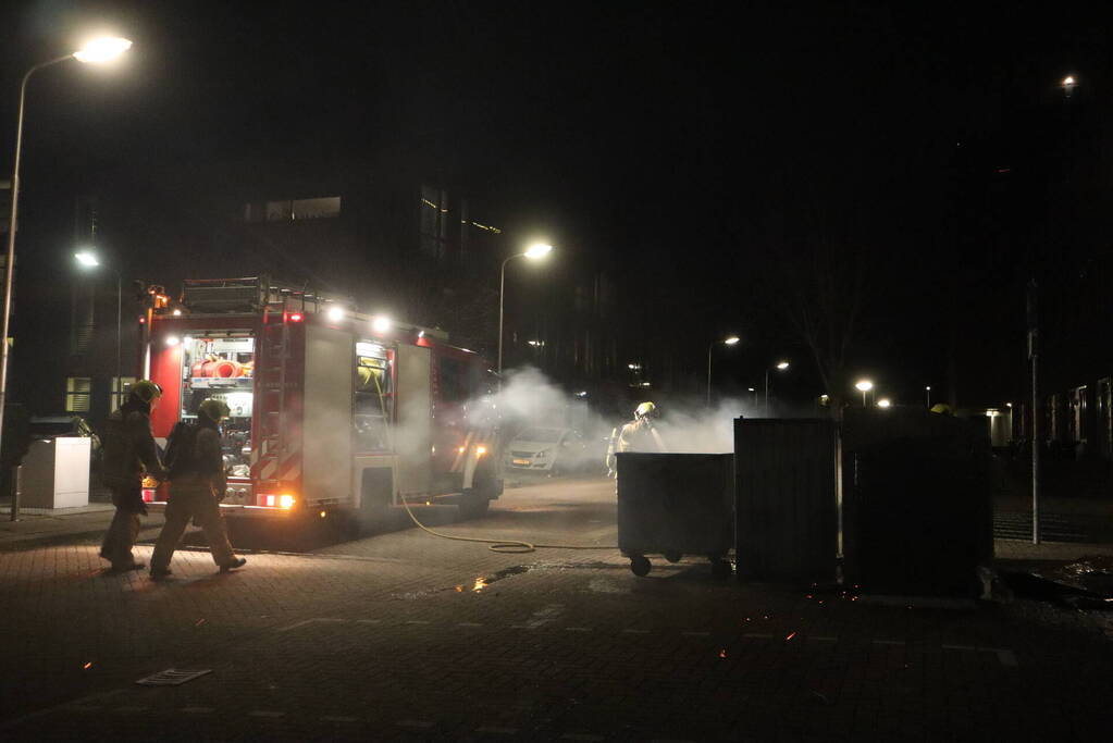 Brandweer blust brandende papiercontainer