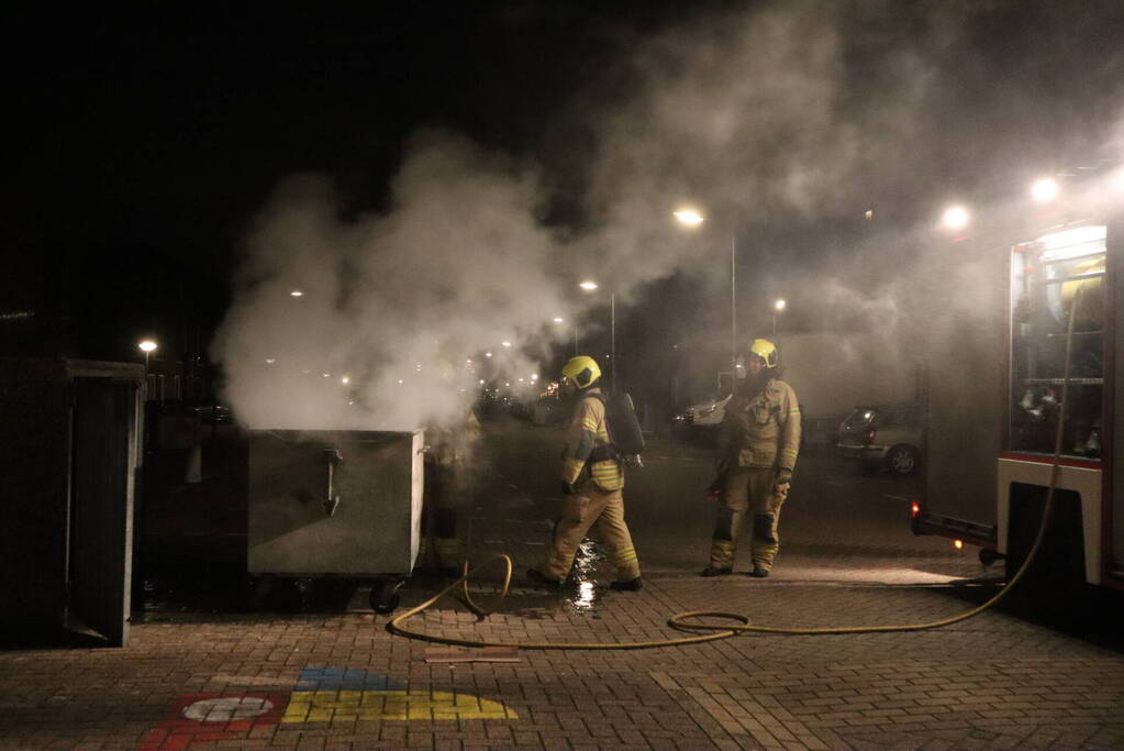 Brandweer blust brandende papiercontainer
