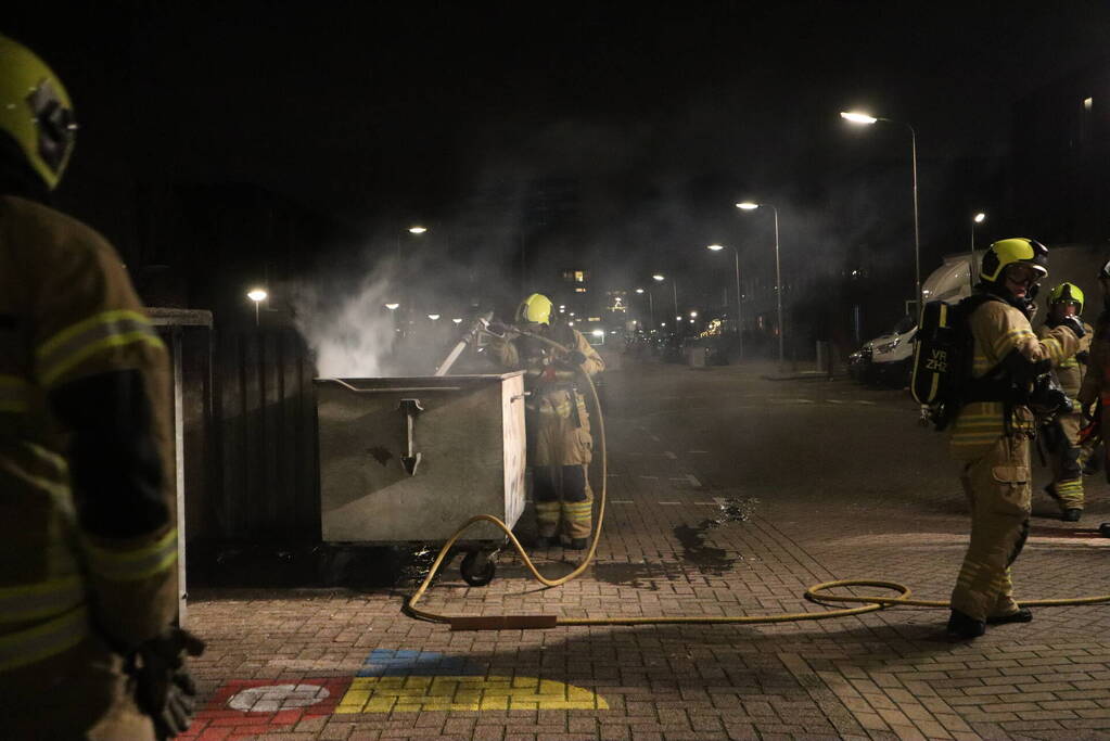 Brandweer blust brandende papiercontainer