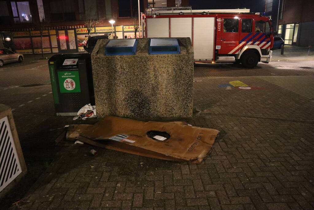 Brandweer blust brandende papiercontainer
