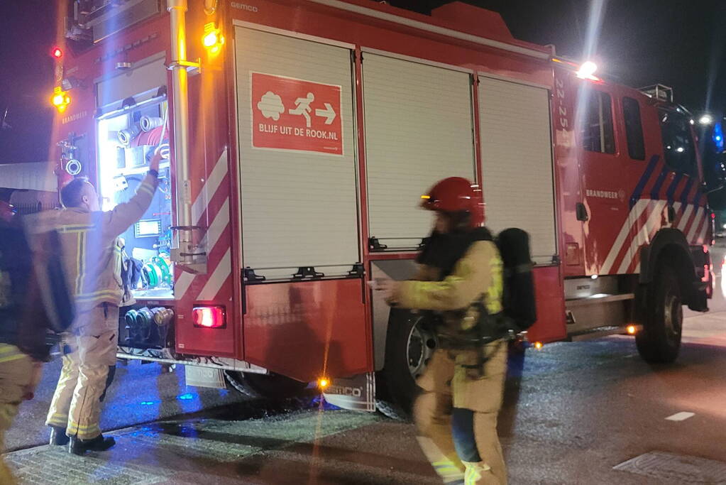 Brandweer blust brandend heg naast pand