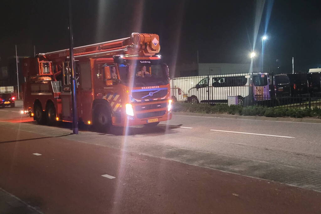 Brandweer blust brandend heg naast pand