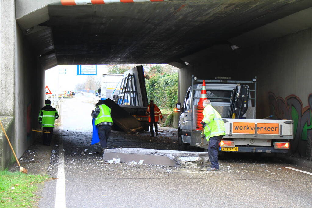 Vrachtwagenchauffeur rijdt met lading tegen spoorviaduct