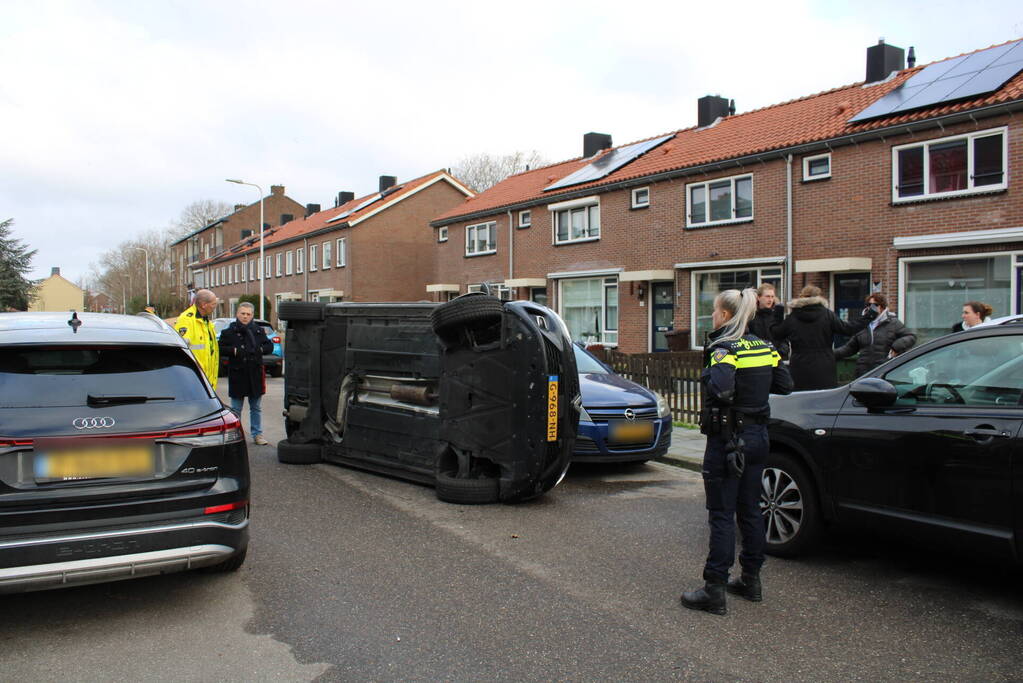 Auto op op zijn zijkant na botsing in woonwijk