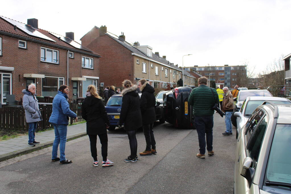 Auto op op zijn zijkant na botsing in woonwijk