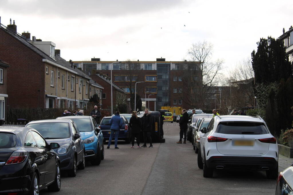 Auto op op zijn zijkant na botsing in woonwijk