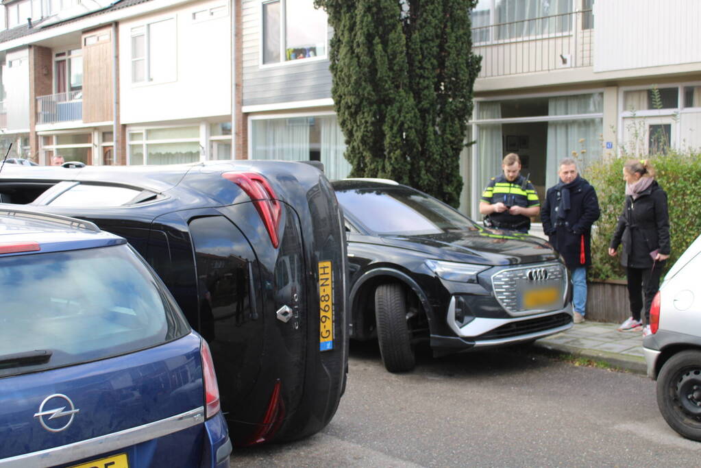 Auto op op zijn zijkant na botsing in woonwijk