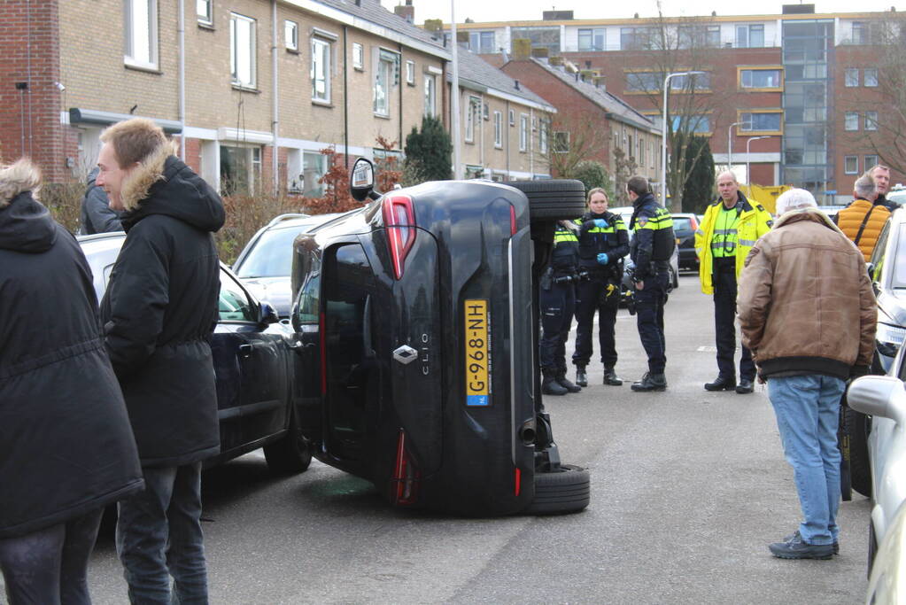 Auto op op zijn zijkant na botsing in woonwijk