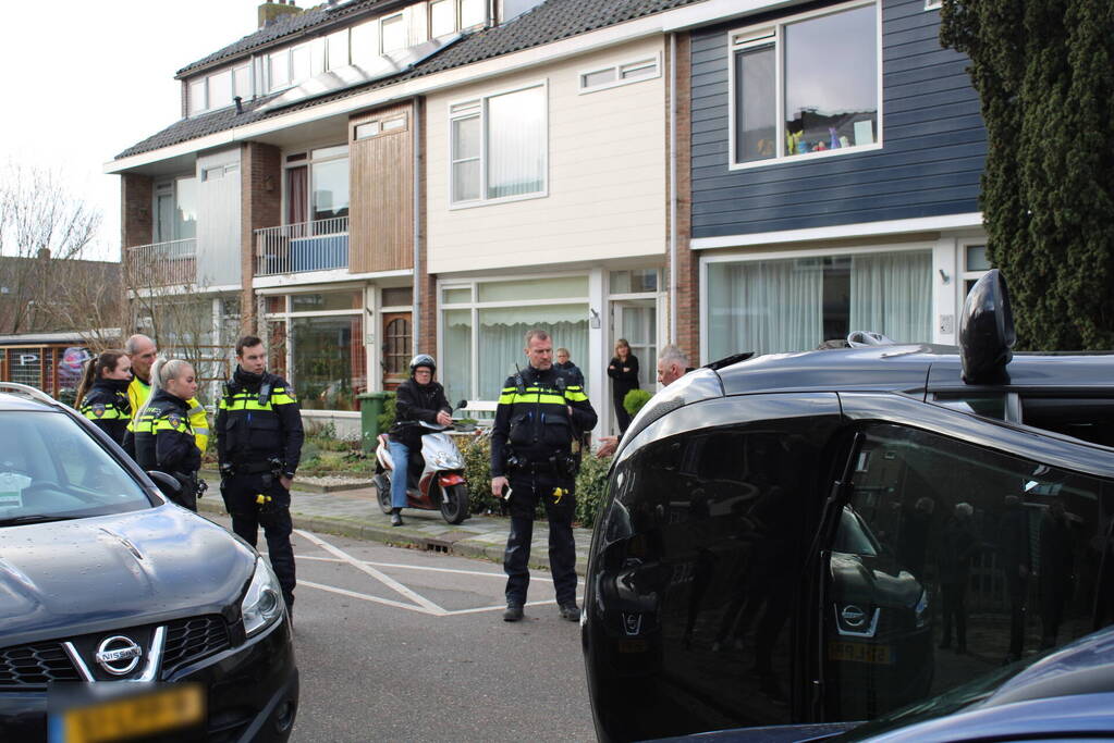 Auto op op zijn zijkant na botsing in woonwijk