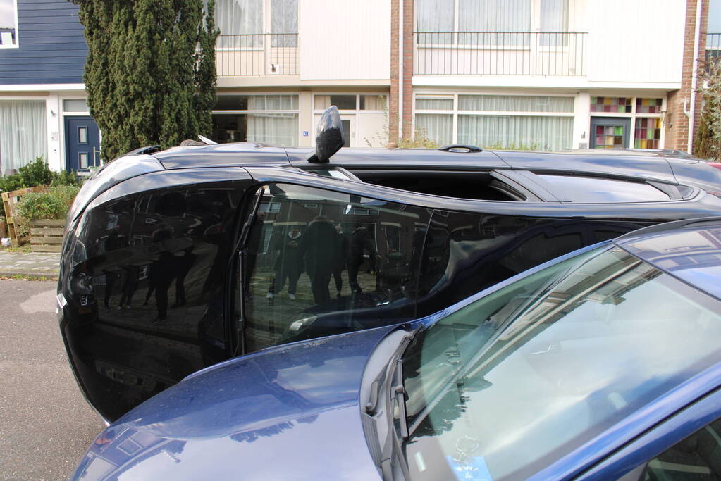 Auto op op zijn zijkant na botsing in woonwijk