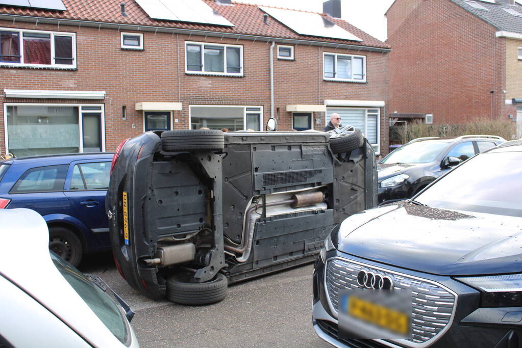 Auto op op zijn zijkant na botsing in woonwijk
