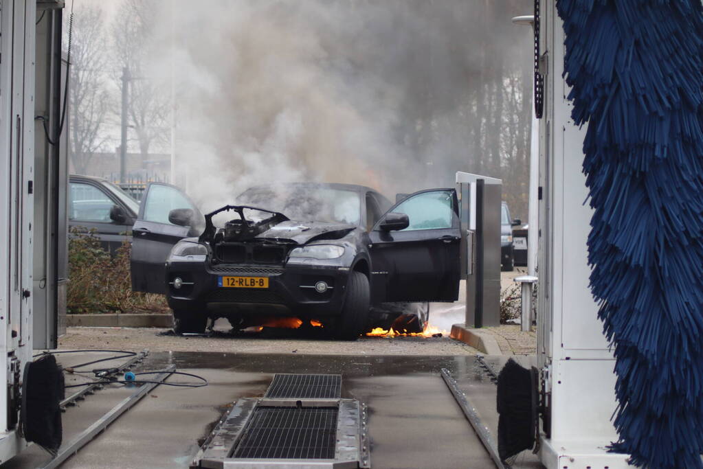 Auto vliegt in brand voor ingang carwash