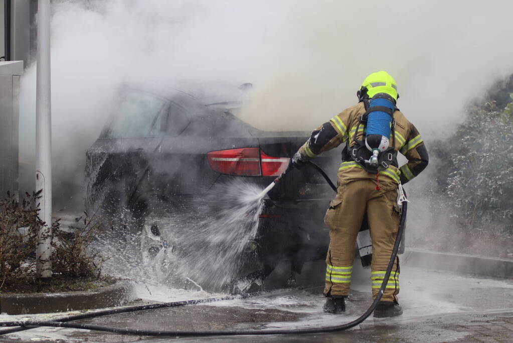 Auto vliegt in brand voor ingang carwash