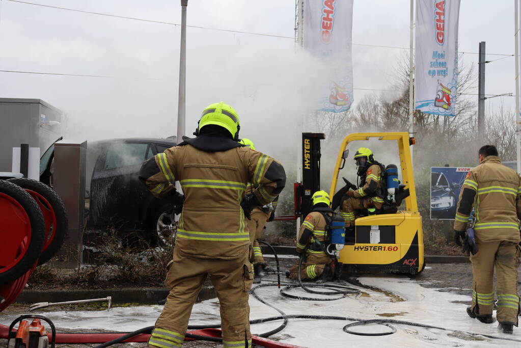 Auto vliegt in brand voor ingang carwash