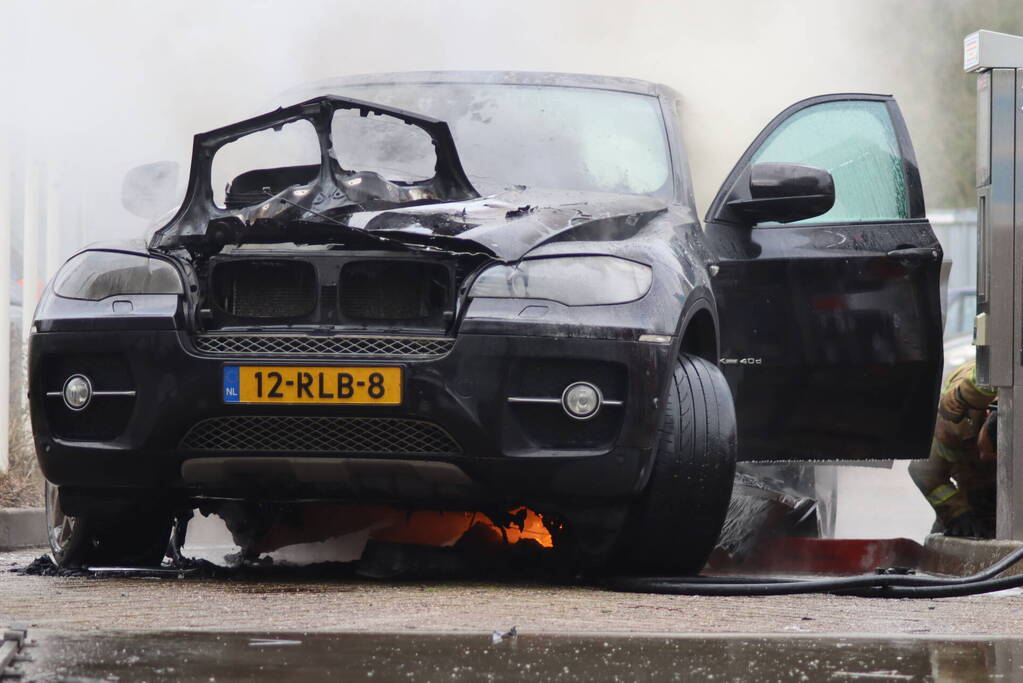 Auto vliegt in brand voor ingang carwash