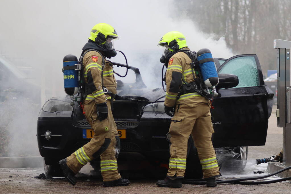 Auto vliegt in brand voor ingang carwash